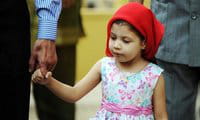 A young Indian Zoroastrian or Parsi girl holds her father\'s hand as they arrive at a fire temple to offer prayers A young Indian Zoroastrian or Parsi girl holds her father\'s hand as they arrive at a fire temple to offer prayers